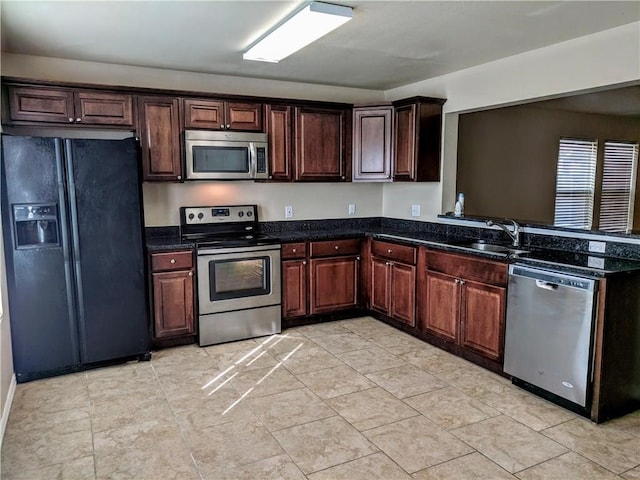 kitchen with stainless steel appliances, dark stone countertops, and sink