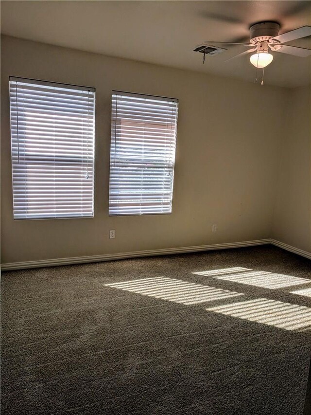 spare room with dark carpet and ceiling fan