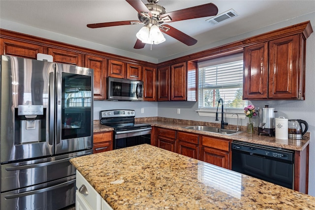 kitchen with light stone countertops, stainless steel appliances, ceiling fan, and sink