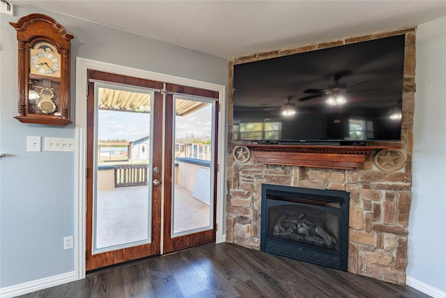 unfurnished living room featuring ceiling fan, dark hardwood / wood-style flooring, a fireplace, and french doors