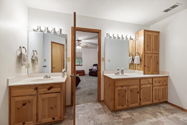 bathroom featuring ceiling fan, lofted ceiling, a textured ceiling, and vanity