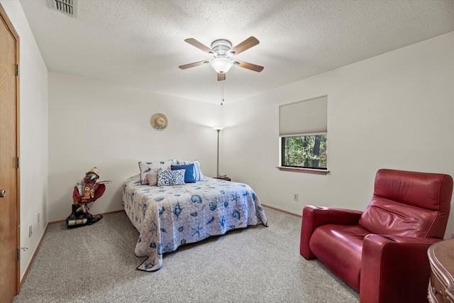 bedroom with ceiling fan, carpet floors, and a textured ceiling