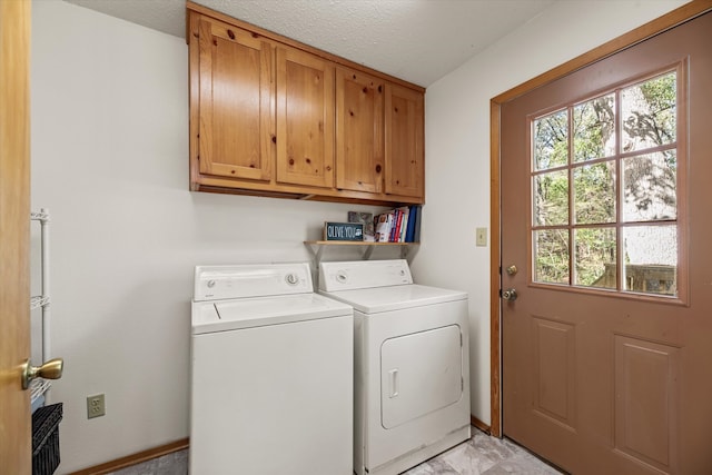 laundry area with washing machine and dryer, cabinets, and a textured ceiling