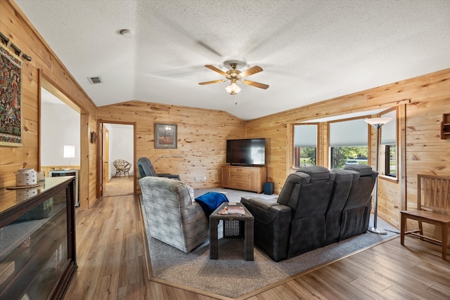 living room featuring wooden walls, light hardwood / wood-style flooring, and lofted ceiling