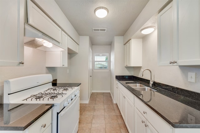 kitchen with white gas stove, white cabinetry, sink, and dark stone counters