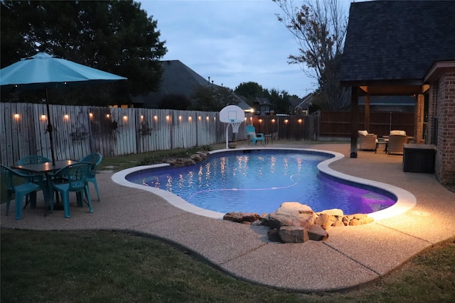 pool at dusk featuring a patio