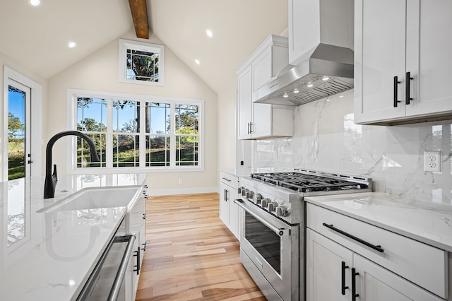 kitchen with tasteful backsplash, wall chimney exhaust hood, stainless steel appliances, light hardwood / wood-style flooring, and beamed ceiling