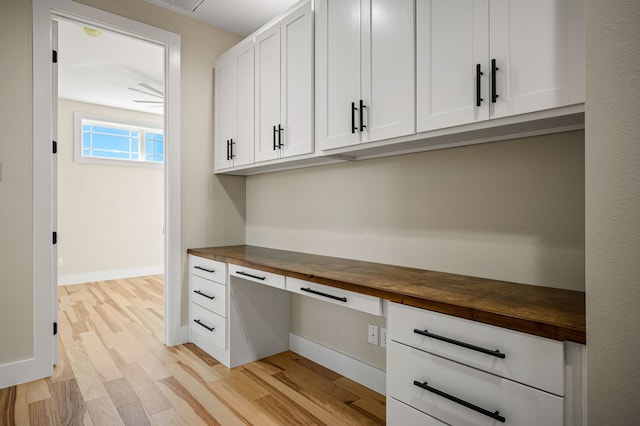 unfurnished office featuring built in desk and light wood-type flooring