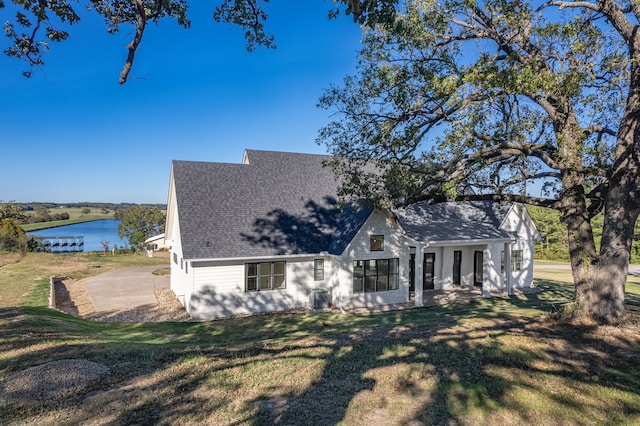 view of front facade with a front yard, a patio, and a water view