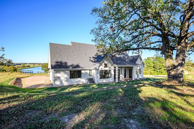 back of property featuring a lawn, central air condition unit, and a water view