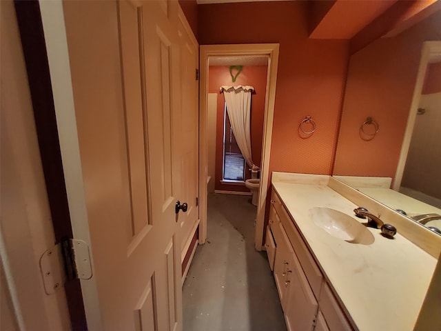 bathroom with vanity, toilet, and concrete flooring