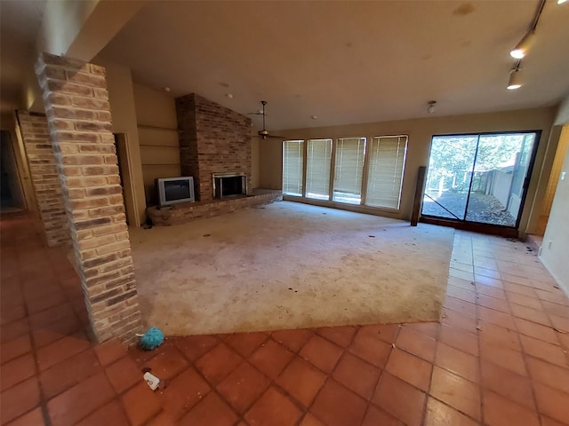 unfurnished living room with track lighting, vaulted ceiling, ceiling fan, light tile patterned floors, and a fireplace