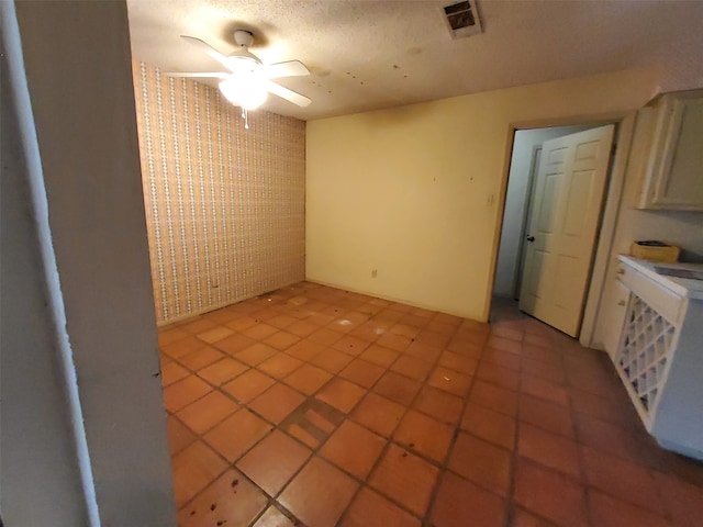 tiled spare room featuring a textured ceiling and ceiling fan