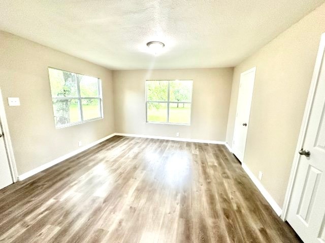 spare room featuring a textured ceiling and dark hardwood / wood-style flooring