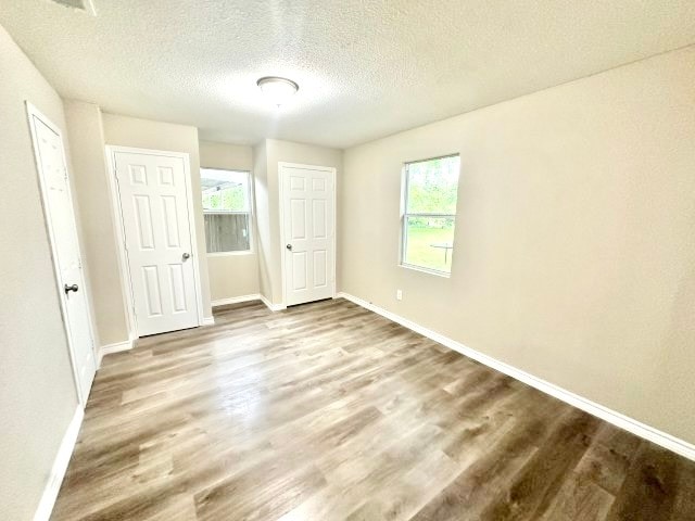 unfurnished bedroom with hardwood / wood-style floors, a textured ceiling, and multiple windows