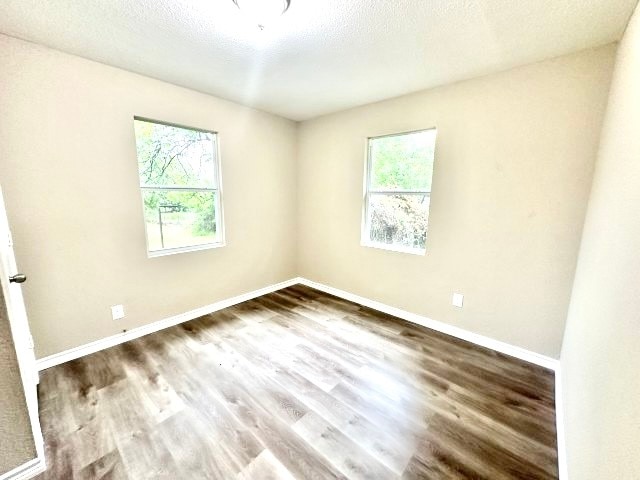 unfurnished room with hardwood / wood-style floors, plenty of natural light, and a textured ceiling