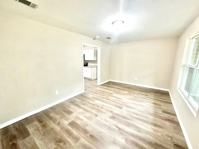 unfurnished room with light hardwood / wood-style floors and a textured ceiling