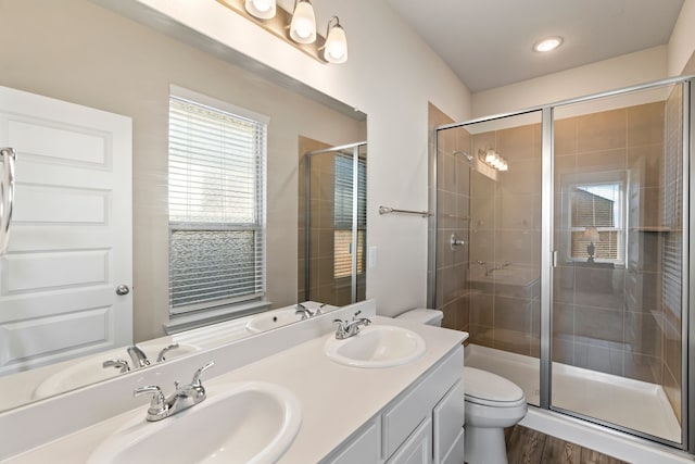 bathroom with hardwood / wood-style flooring, vanity, toilet, and a shower with shower door