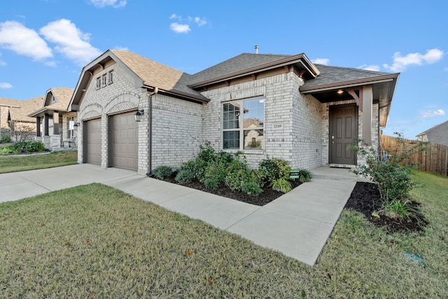 french country home featuring brick siding, roof with shingles, an attached garage, and a front yard