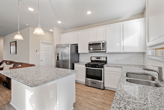 kitchen with white cabinets, hanging light fixtures, sink, light wood-type flooring, and appliances with stainless steel finishes