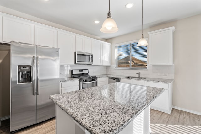 kitchen featuring stainless steel appliances, a kitchen island, hanging light fixtures, and white cabinetry