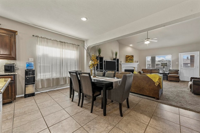 tiled dining area with a textured ceiling, ceiling fan, and lofted ceiling