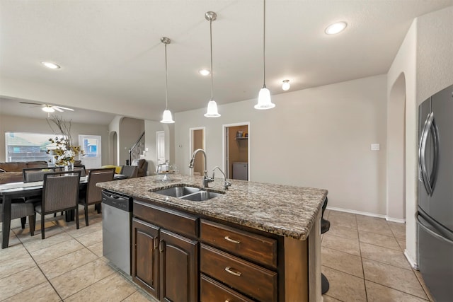 kitchen with appliances with stainless steel finishes, dark brown cabinets, sink, a center island with sink, and decorative light fixtures