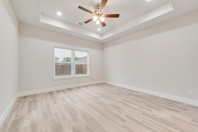 unfurnished room featuring ceiling fan, a raised ceiling, and light hardwood / wood-style flooring