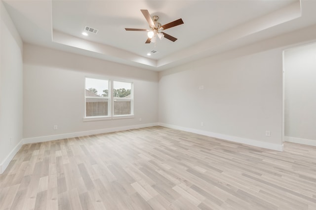 unfurnished room with a tray ceiling, ceiling fan, and light hardwood / wood-style floors