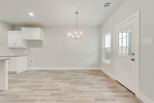 unfurnished dining area with light hardwood / wood-style floors and an inviting chandelier