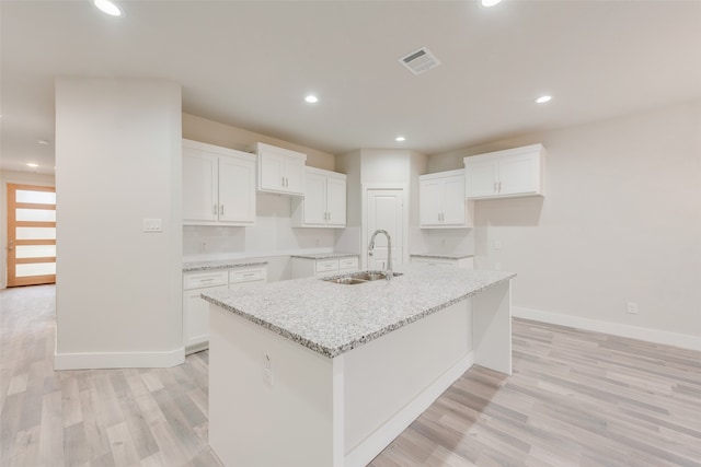 kitchen with white cabinets, sink, and a kitchen island with sink