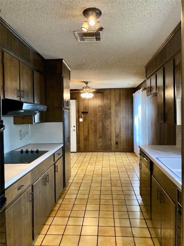 kitchen with dark brown cabinetry, wooden walls, and a textured ceiling