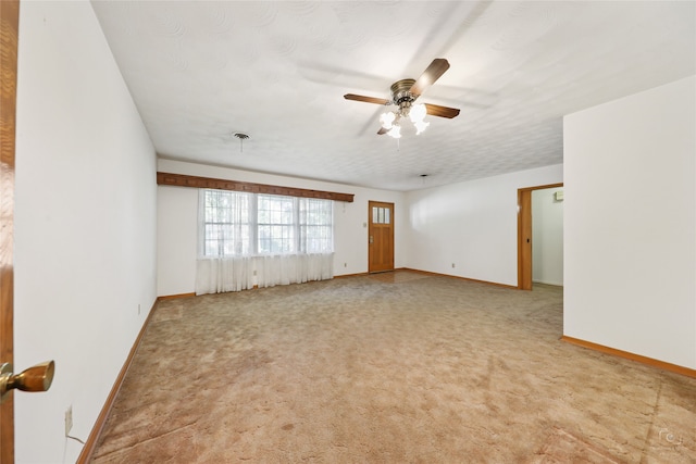 spare room featuring ceiling fan, light colored carpet, and a textured ceiling