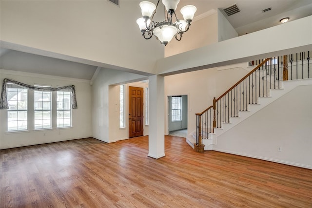 foyer entrance featuring light hardwood / wood-style flooring, high vaulted ceiling, and a chandelier