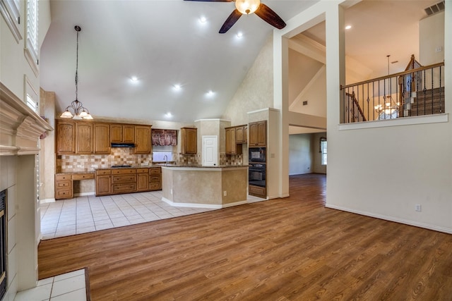 kitchen with light hardwood / wood-style flooring, high vaulted ceiling, black appliances, and decorative light fixtures