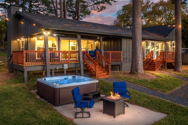 back house at dusk with a fire pit, a patio, a wooden deck, and a hot tub