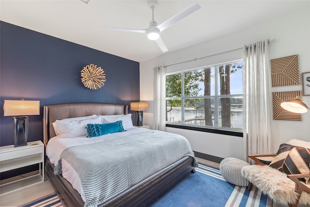 bedroom with a water view and ceiling fan