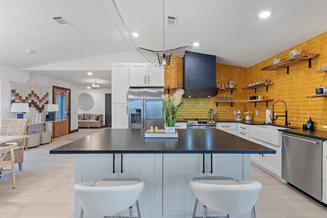 kitchen featuring sink, stainless steel appliances, lofted ceiling, decorative backsplash, and white cabinets