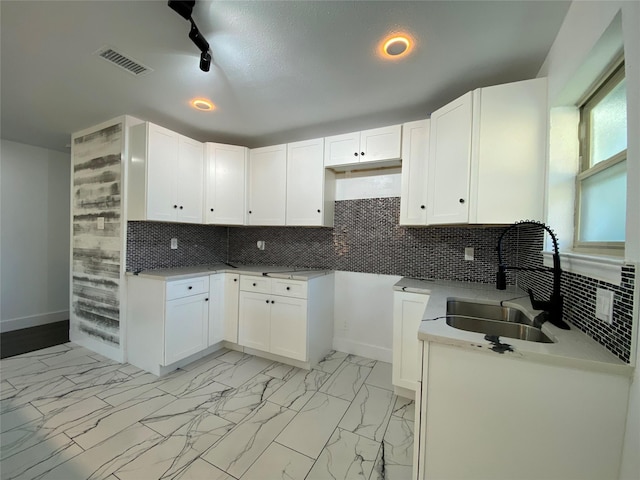 kitchen featuring backsplash, white cabinetry, and sink