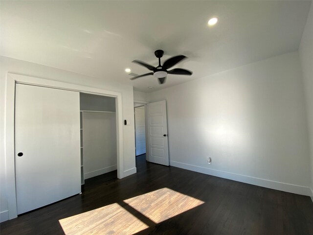 unfurnished bedroom with ceiling fan, dark wood-type flooring, and a closet