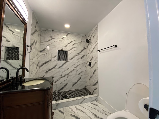 bathroom featuring tiled shower, vanity, and toilet