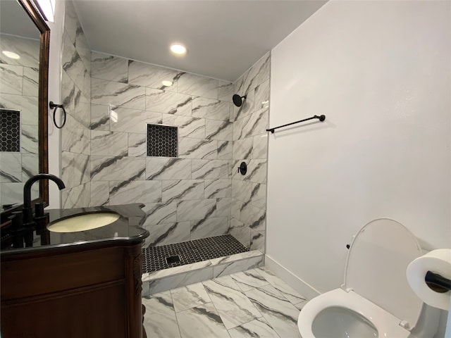 bathroom with vanity, toilet, and tiled shower