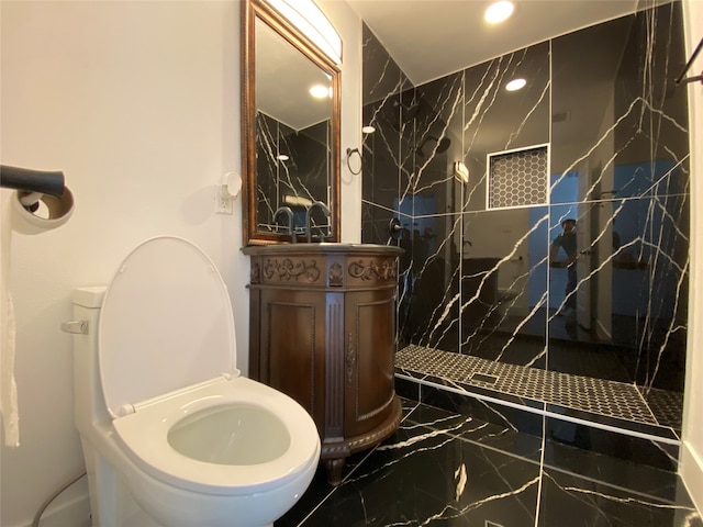 bathroom with a tile shower, vanity, and toilet