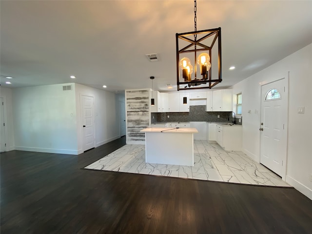 kitchen with white cabinets, decorative light fixtures, light hardwood / wood-style floors, and a center island