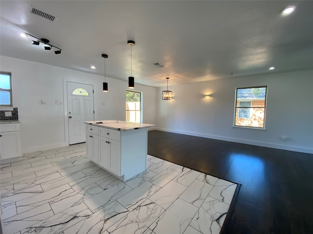 kitchen featuring white cabinets, pendant lighting, a kitchen island, and a wealth of natural light