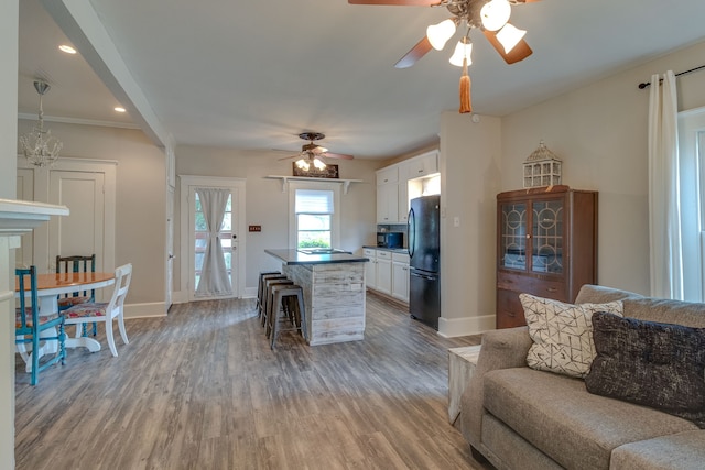 kitchen featuring white cabinets, hardwood / wood-style flooring, a breakfast bar area, and black appliances