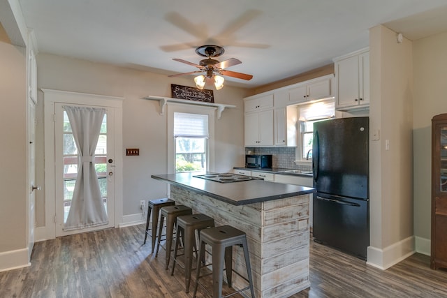 kitchen featuring a kitchen bar, tasteful backsplash, black appliances, dark hardwood / wood-style floors, and white cabinetry