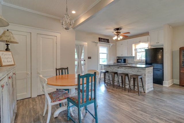 dining space with ceiling fan with notable chandelier, light hardwood / wood-style floors, and crown molding