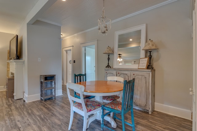 dining area featuring crown molding, a fireplace, dark wood-type flooring, and ceiling fan with notable chandelier