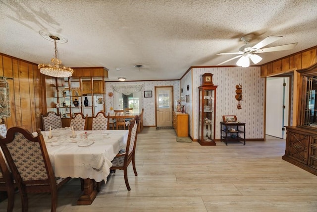 dining area featuring a textured ceiling, wooden walls, and light hardwood / wood-style flooring